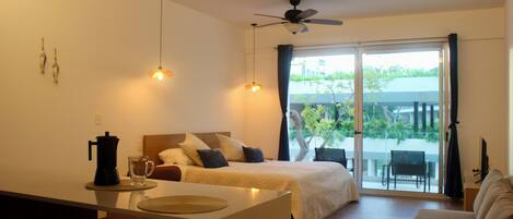 A modern hotel room with a bed, a dining area, and a balcony.