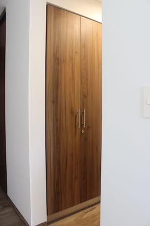 A wooden wardrobe with two doors and a handle, against a white wall. - Brand-New Studio with 4 Pool Access at The Leaf Playacar, | All-Inclusive (Playa del Carmen)