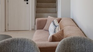A living room with a beige sofa, a patterned throw pillow, and a staircase in the background. - Metatulia Villa 6 – Private Pool, Jacuzzi & Views (Plakias)