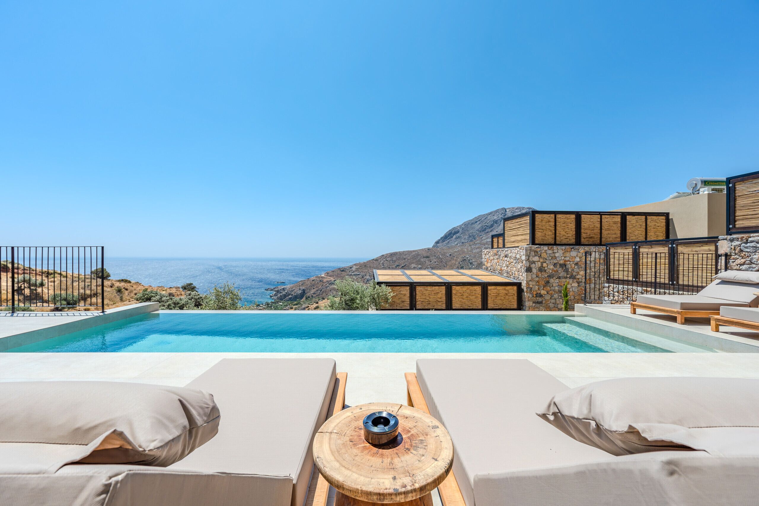 A poolside view with lounge chairs and a view of the sea.