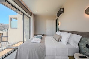Quarto de hotel moderno com uma cama grande, mesa de cabeceira, janela com vista para o exterior e ar condicionado fixado na parede.