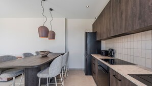 A modern kitchen with a dark wood cabinet, a black refrigerator, and a built-in oven. - Metatulia Villa 6 – Private Pool, Jacuzzi & Views (Plakias)