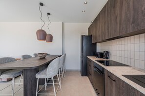 Eine moderne Küche mit einem dunklen Holzschrank, einem schwarzen Kühlschrank und einem eingebauten Backofen.