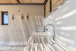 A modern bathroom with a large window, a built-in sink, and a bamboo ceiling. - Metatulia Villa 6 – Private Pool, Jacuzzi & Views (Plakias)
