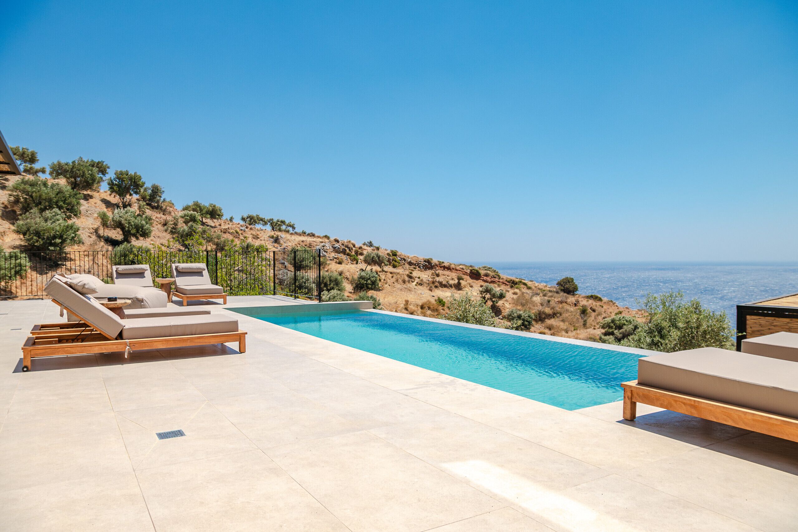 Ein Poolbereich mit Liegestühlen und Meerblick.