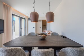 A modern dining room with a dark wooden table, two pendant lights, and a bowl of fruit. - Metatulia Villa 6 – Private Pool, Jacuzzi & Views (Plakias)