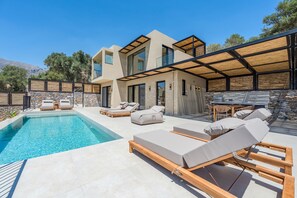 Uma casa moderna com piscina, área de estar externa e um muro de pedra.