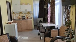 Un espace de vie compact comprenant un coin cuisine, un espace repas et un coin salon.