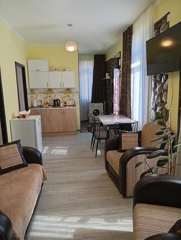 A compact living space with a kitchenette, dining area, and seating.