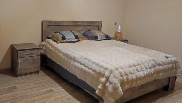 Une chambre à coucher avec un lit en bois, une table de chevet et un luminaire suspendu.