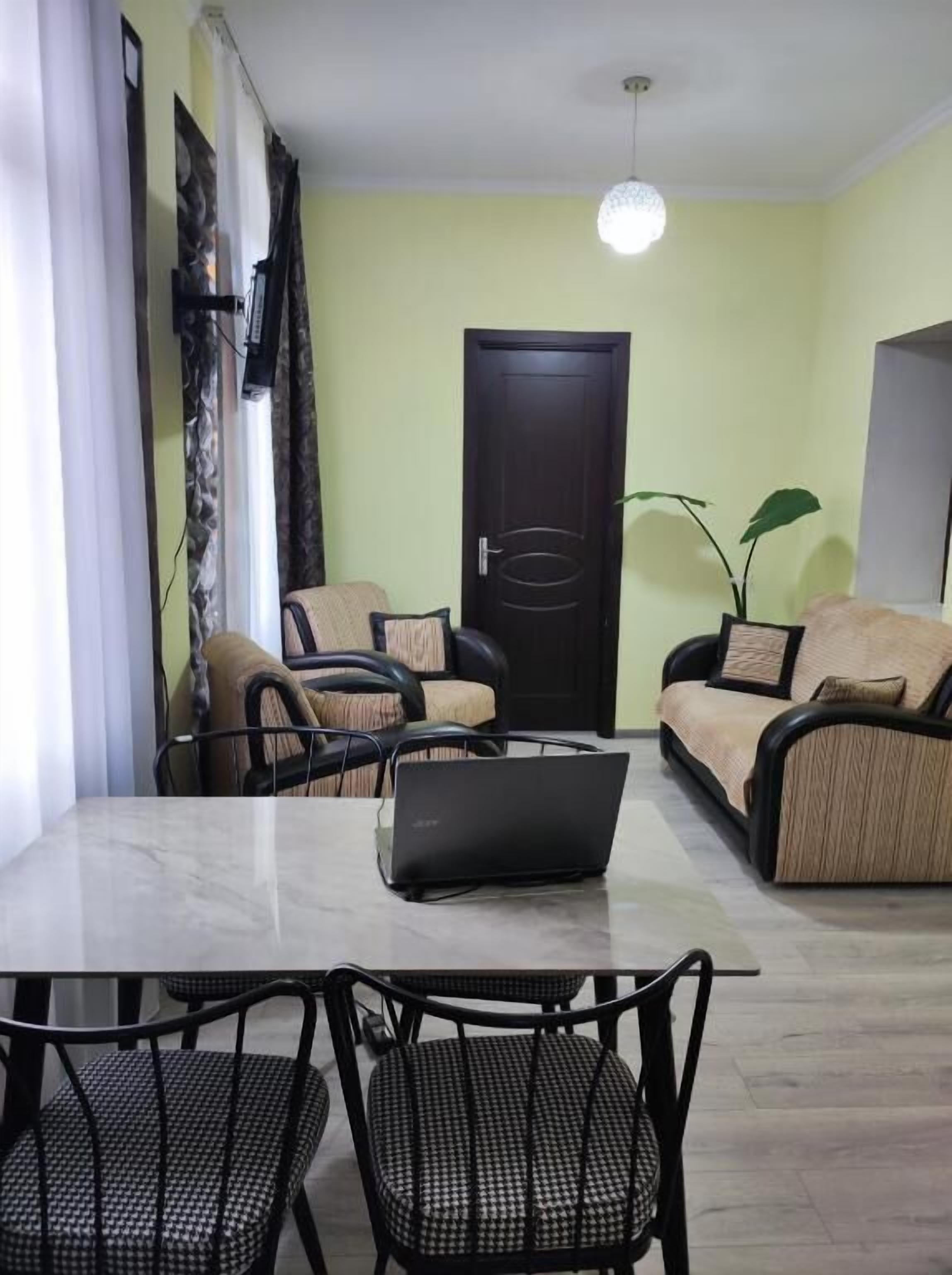 Un comedor con una mesa, sillas, una computadora portátil, un sofá y una puerta.