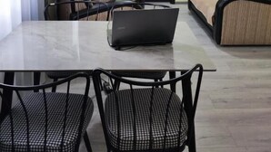 Un espace repas comprenant une table, des chaises, un ordinateur portable, un canapé et une porte.