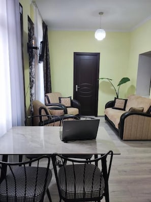 Un comedor con una mesa, sillas, una computadora portátil, un sofá y una puerta.