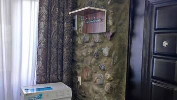 A laundry area with a washing machine, a stone wall, a door, and a window with curtains.