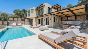 Uma casa moderna com piscina, área de estar externa e um muro de pedra.