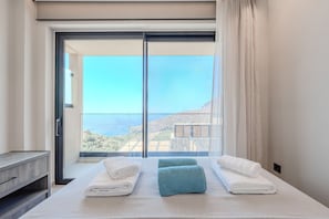 Ein Hotelzimmer mit einem großen Bett, zwei Handtüchern, einem Nachttisch und Bergländerey durch eine Schiebetür.