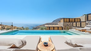 Vista da piscina com espreguiçadeiras e vista para o mar.