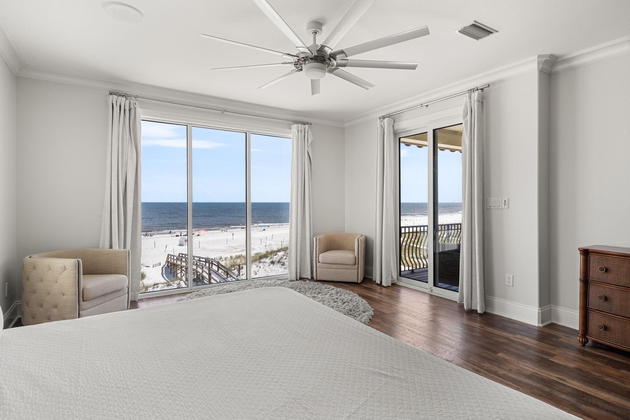 Un dormitorio amplio con una cama grande, un ventilador de techo y vistas a la playa.