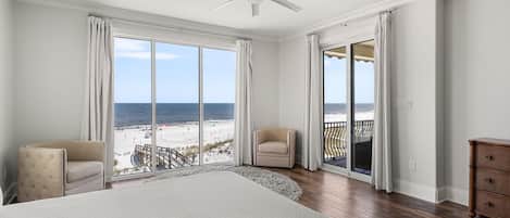 Un dormitorio amplio con una cama grande, un ventilador de techo y vistas a la playa.