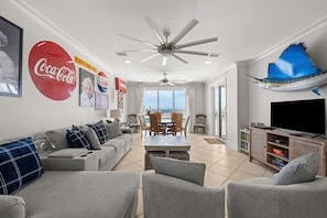 A spacious living room with a sofa set, a dining table, and a television. - The Hammock Dunes Collection (Orange Beach)
