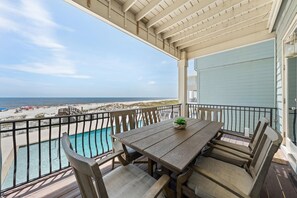 A wooden deck with a pool, overlooking a beach. - The Hammock Dunes Collection (Orange Beach)