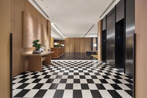A hotel lobby with a checkered floor, wooden paneling, a reception desk, and a reception area. - Voco Shenyang Golden Corridor By Ihg (Shenyang)