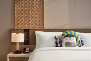 A hotel room with a bed, a nightstand with a lamp, a phone, and a decorative pillow. - Voco Shenyang Golden Corridor By Ihg (Shenyang)
