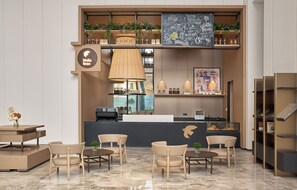 L'intérieur d'un café moderne, avec des tables, un comptoir et un menu écrit à la craie sur un tableau noir.