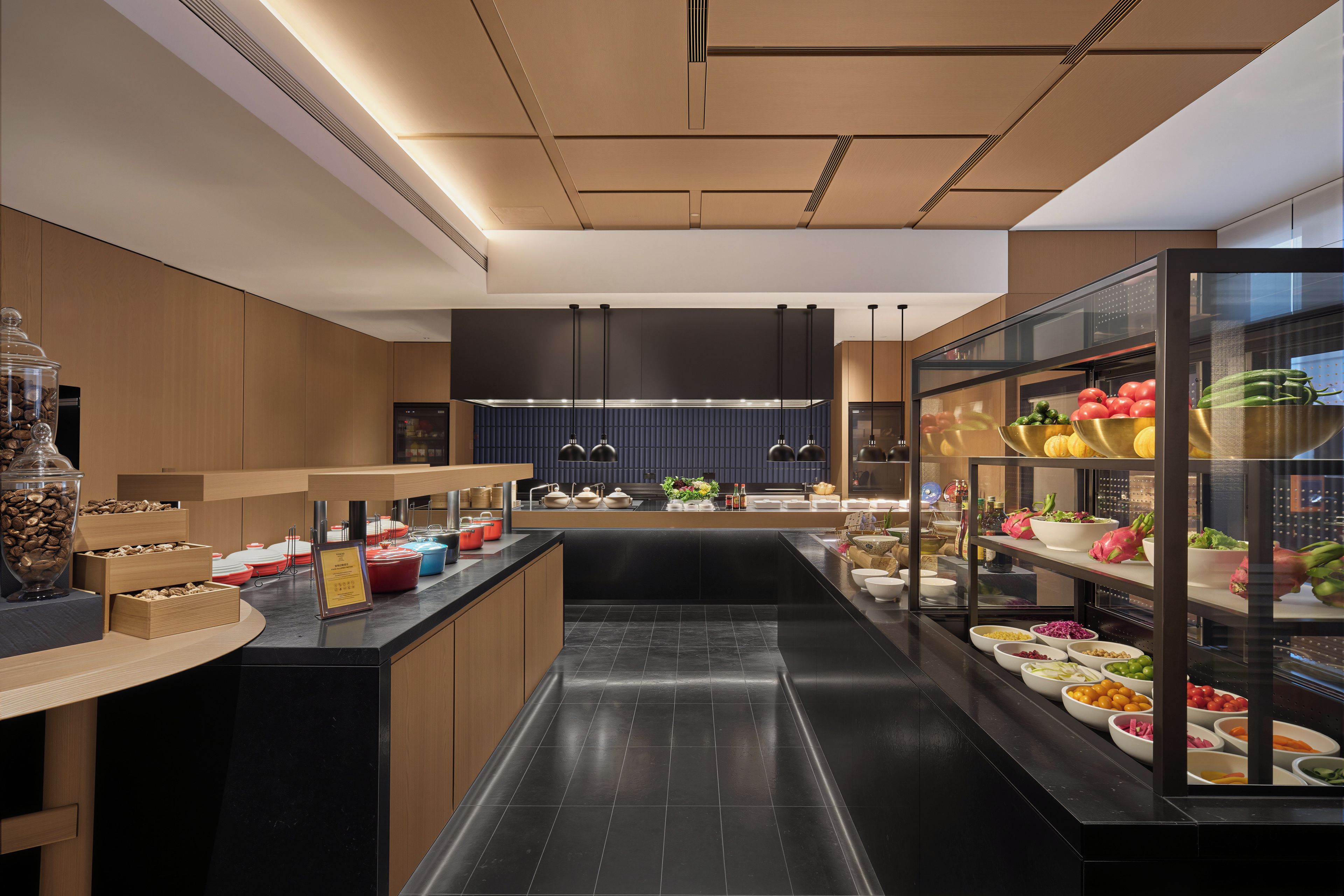 A modern kitchen with a central island, black countertops, and a variety of cooking utensils and appliances.