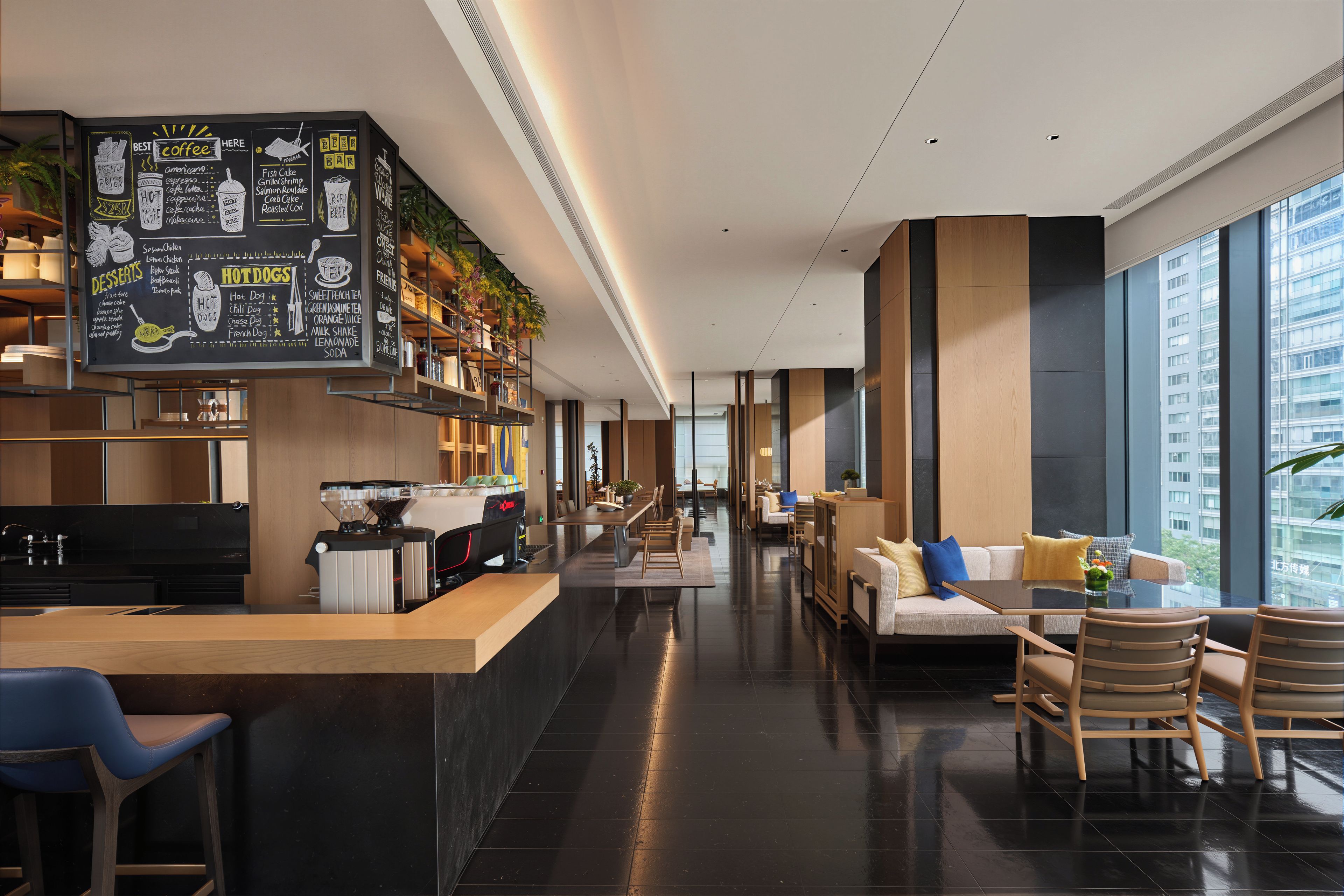 A modern cafe with a chalkboard menu, seating area, and large windows.