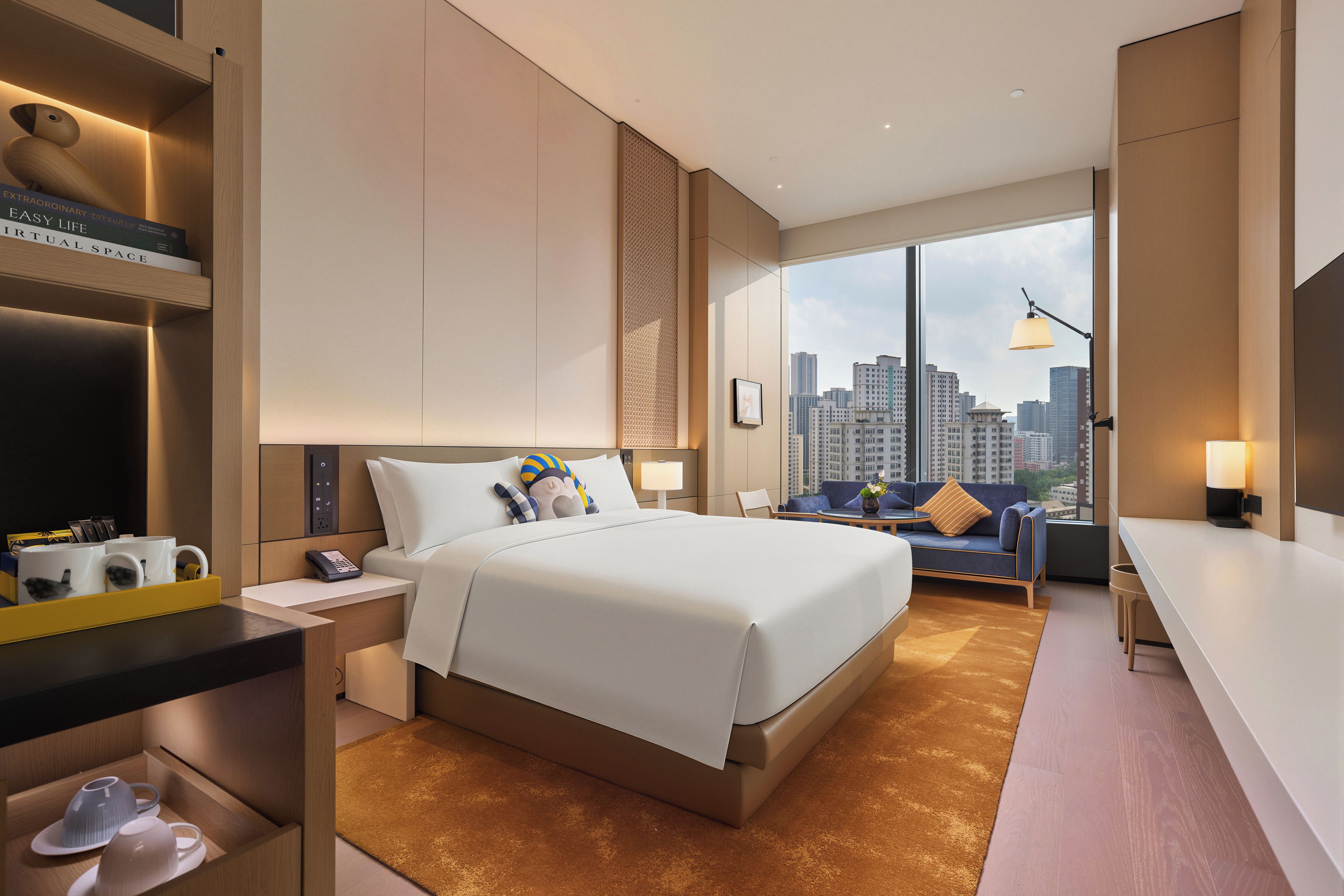 Habitación de hotel moderna con una cama grande, un escritorio y vistas al horizonte de la ciudad.
