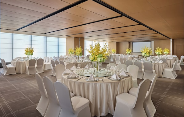 A conference room with round tables, white chairs, and floral centerpieces. - Voco Shenyang Golden Corridor By Ihg (Shenyang)