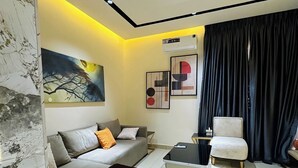 Un dormitorio moderno con cama, sofá, sillón y un cuadro en la pared.