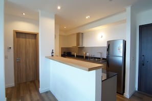 A modern kitchen with a wooden door, a built-in island, and a stainless steel refrigerator. - Lake, Mountains, and Comfort · Bright and Cozy Apartment (San Carlos de Bariloche)