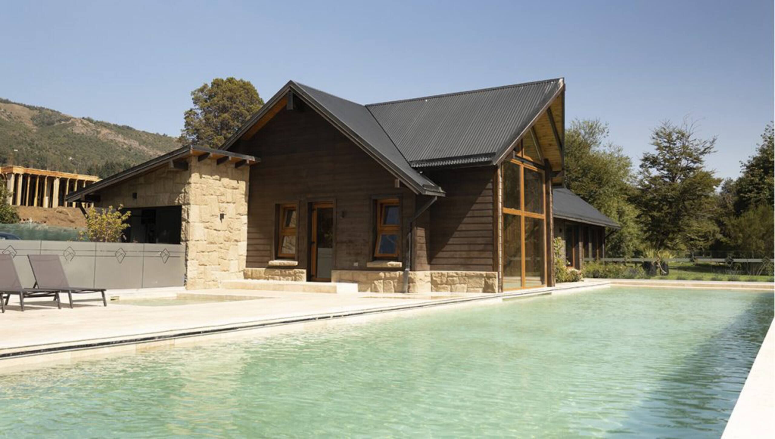 Una cabaña de madera de dos pisos con una piscina delantera.