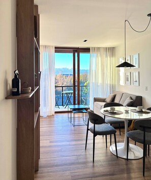 A modern living room with a dining area, large windows, and a view of the outdoors. - Lake, Mountains, and Comfort · Cozy and Bright Apartment (San Carlos de Bariloche)