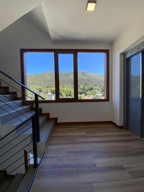 A staircase leading to a landing with a large window overlooking a mountainous landscape. - Lake, Mountains, and Comfort · Bright and Cozy Apartment (San Carlos de Bariloche)