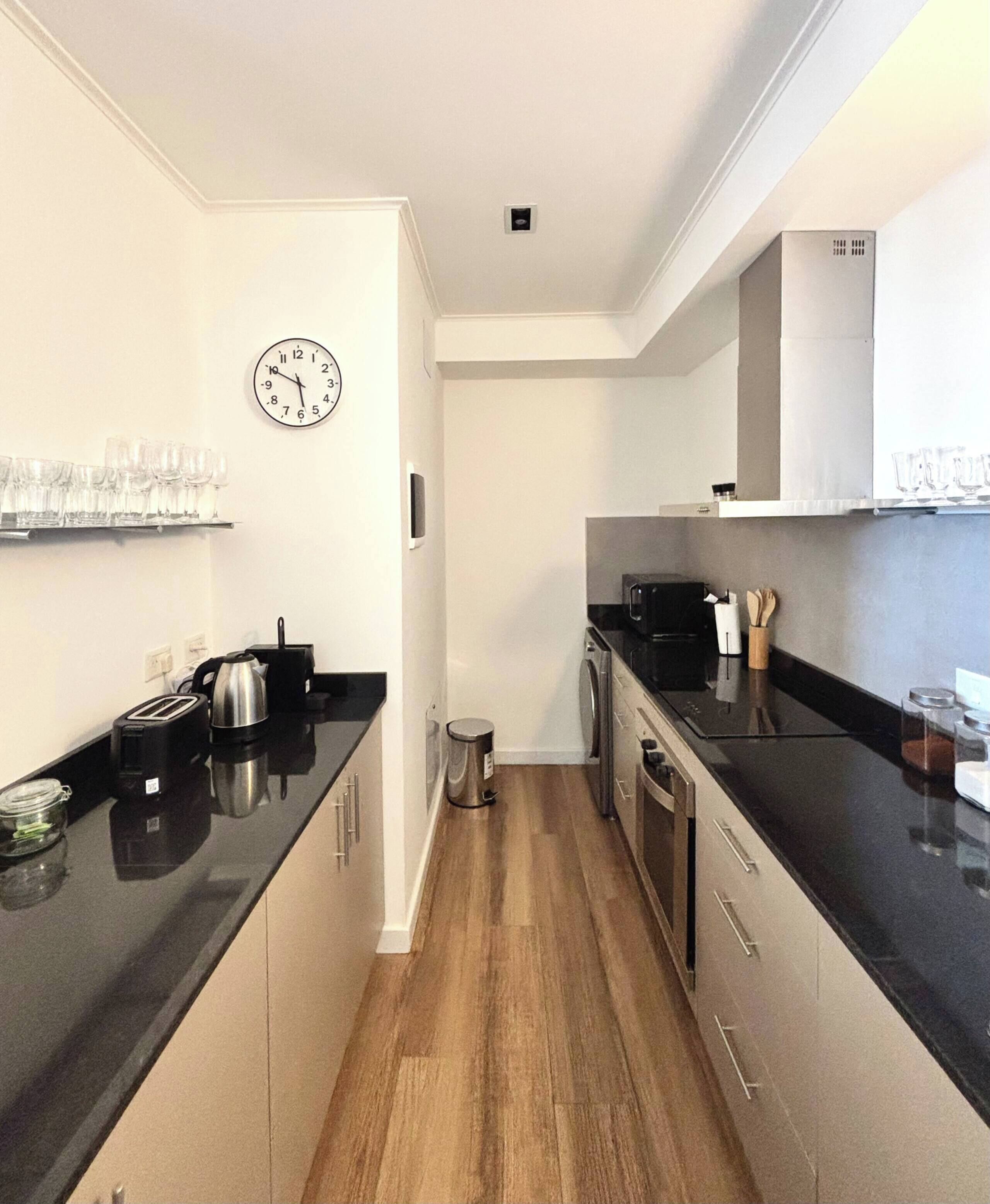 Eine moderne Küche mit schwarzen Arbeitsplatten, Edelstahlgeräten und Holzböden.