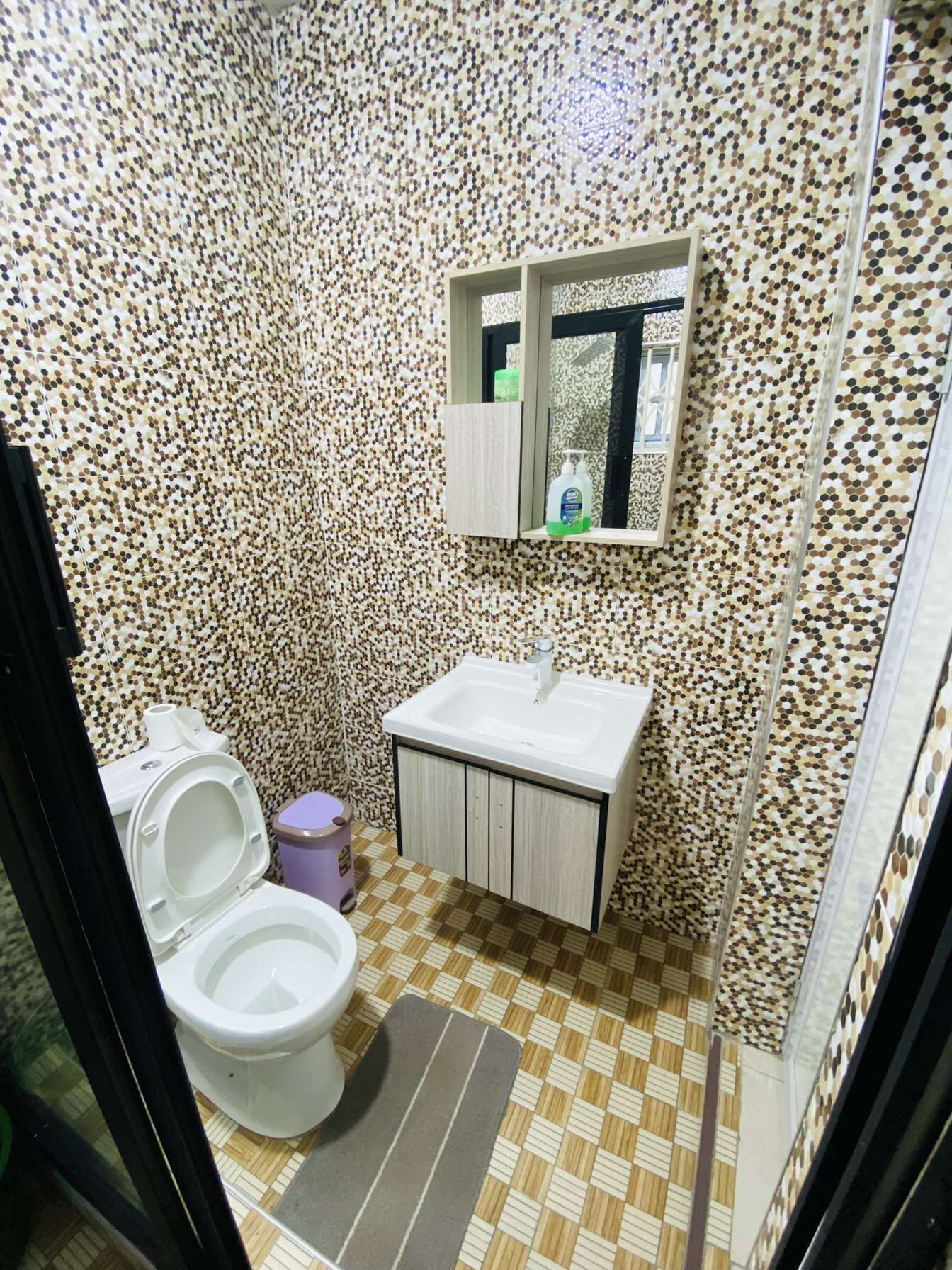 A bathroom with a toilet, sink, and mirror.