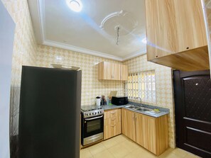A kitchen with a refrigerator, stove, microwave, and wooden cabinets. - your comfort is our priority (Accra)