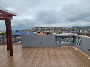 A balcony with a view of a residential area and a cloudy sky. - your comfort is our priority (Accra)