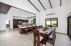 A modern kitchen with a central island, dining area with a long table and chairs, and a large window providing a view. - Beautiful house with private pool Hacienda Pinilla (Hacienda Pinilla)