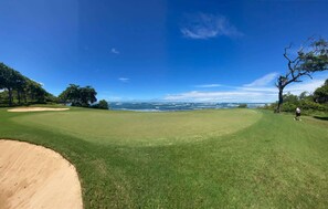 A golf course with a clear view of the ocean and a person walking on the grass. - Beautiful house with private pool Hacienda Pinilla (Hacienda Pinilla)