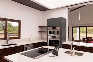 A modern kitchen with a central island, built-in ovens, and a large window providing a view of the outdoors. - Beautiful house with private pool Hacienda Pinilla (Hacienda Pinilla)