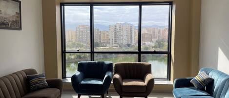 Una sala de estar con un ventanal grande, dos sillones, un sofá y una mesita.