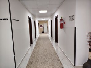 Un pasillo con puertas que dicen 'ENSEUR' y 'ASSEINSUF' dando a varios cuartos.