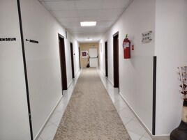 Un pasillo con puertas que dicen 'ENSEUR' y 'ASSEINSUF' dando a varios cuartos.