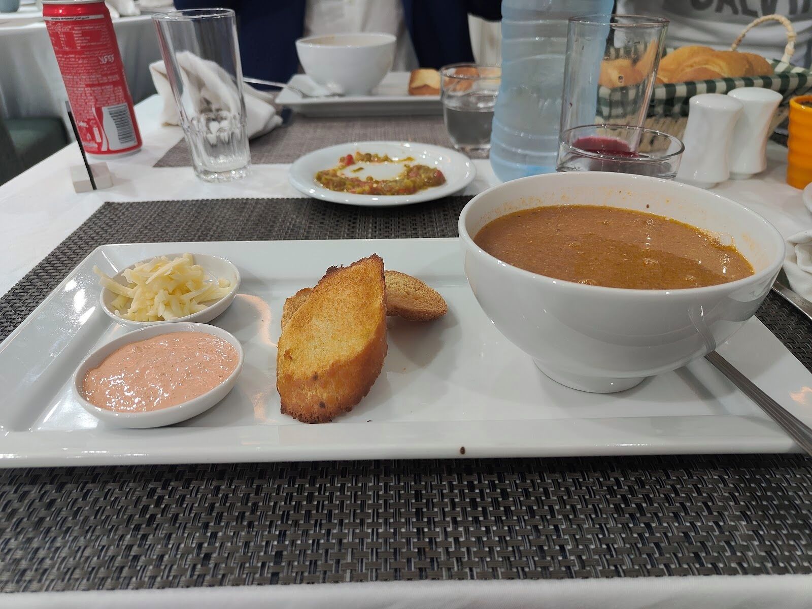 A meal tray with soup, bread, and two dipping sauces.