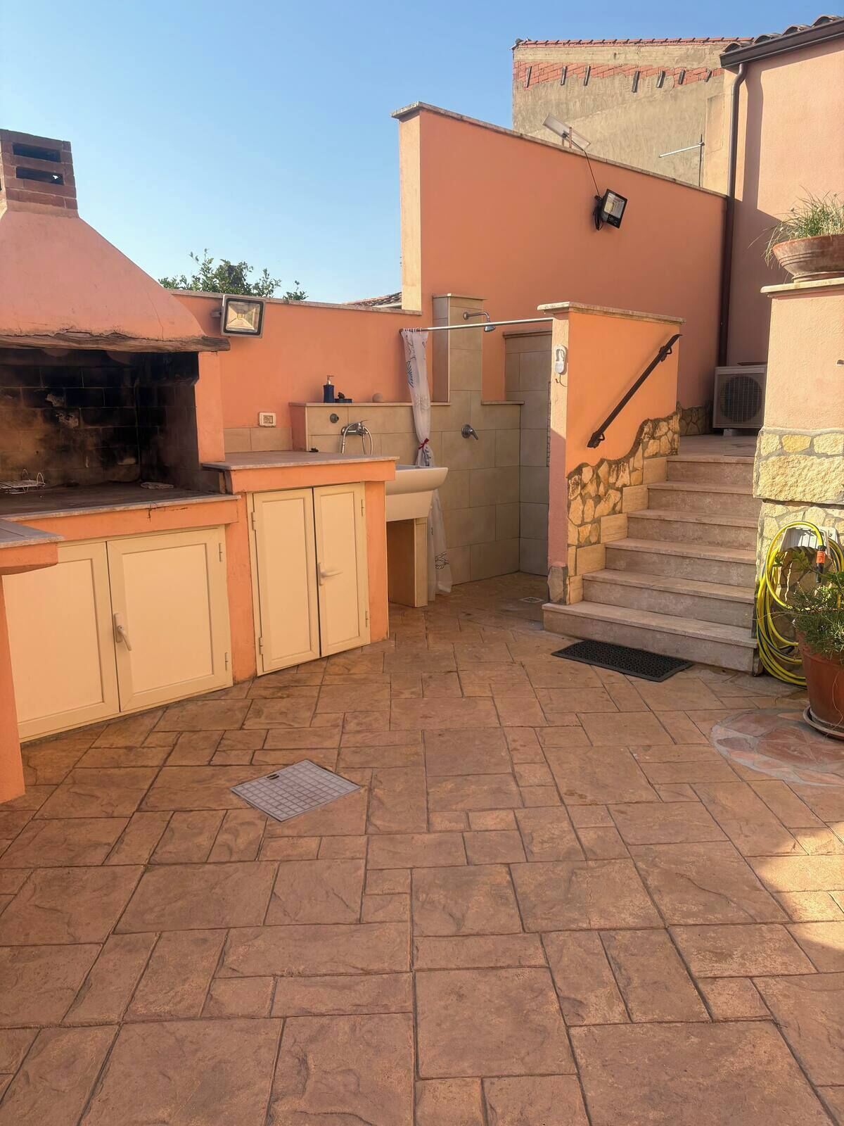 A patio with a barbecue grill, a sink, and a shower area.