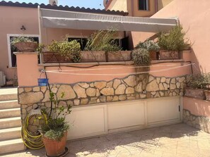 A building with a stone facade, a covered entrance, and potted plants. - Casa Mare Teulada (Teulada)